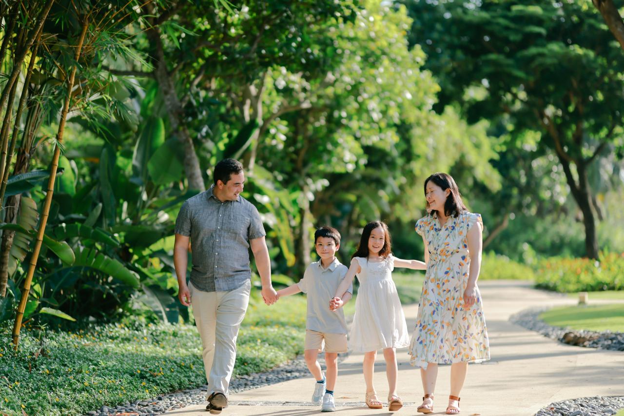 Family walking on a path in a lush garden.