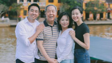 A family poses for a photo outdoors by a river.